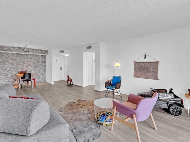 900 NE 195th St Unit 504, Miami, FL 33179 - living area with visible vents, baseboards, a textured ceiling, and wood finished floors
