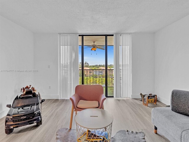 900 NE 195th St Unit 504, Miami, FL 33179 - living room featuring expansive windows, a textured ceiling, wood finished floors, baseboards, and ceiling fan