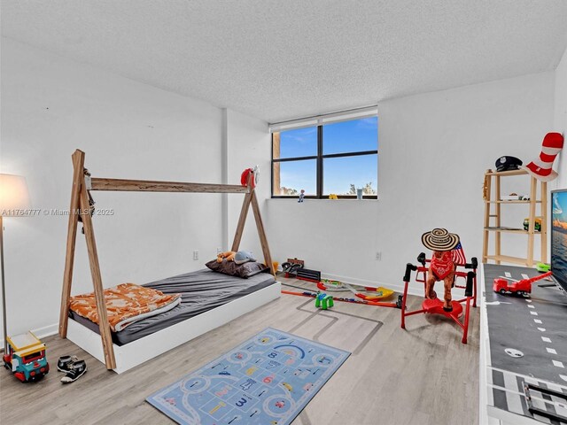 900 NE 195th St Unit 504, Miami, FL 33179 - bedroom featuring a textured ceiling, baseboards, and wood finished floors