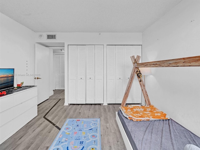 900 NE 195th St Unit 504, Miami, FL 33179 - unfurnished bedroom with visible vents, a textured ceiling, two closets, and wood finished floors