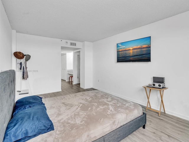900 NE 195th St Unit 504, Miami, FL 33179 - bedroom with baseboards, wood finished floors, visible vents, and a textured ceiling