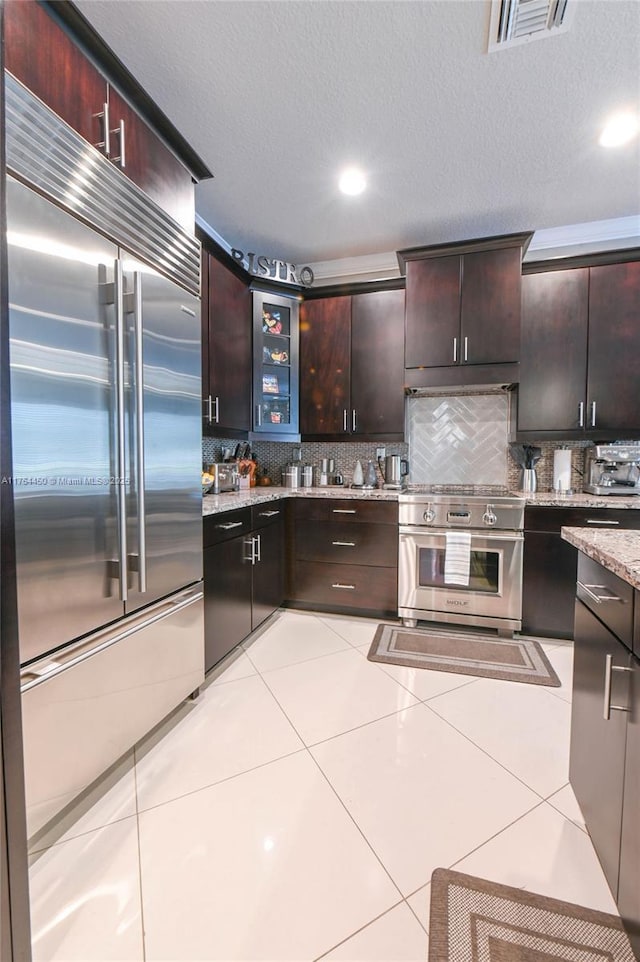 747 NE 193rd Ter, Miami, FL 33179 - kitchen with decorative backsplash, high quality appliances, visible vents, and light tile patterned floors
