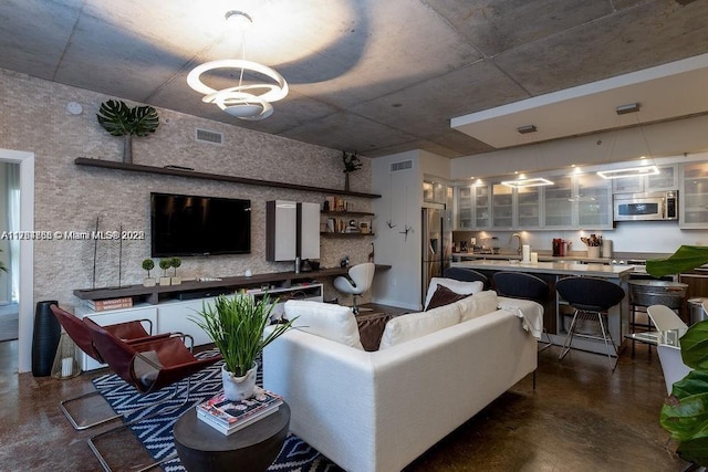 living area with an inviting chandelier, visible vents, and concrete floors