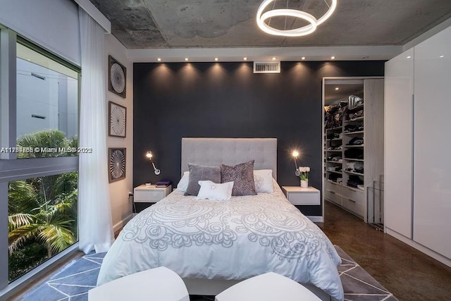 bedroom featuring visible vents, concrete floors, and an accent wall