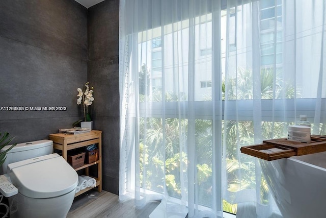 bathroom featuring plenty of natural light, toilet, and wood finished floors