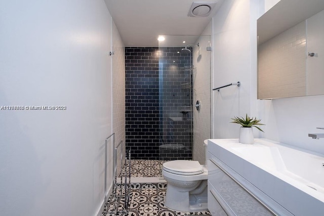 full bath featuring a tile shower, tile patterned flooring, toilet, and vanity