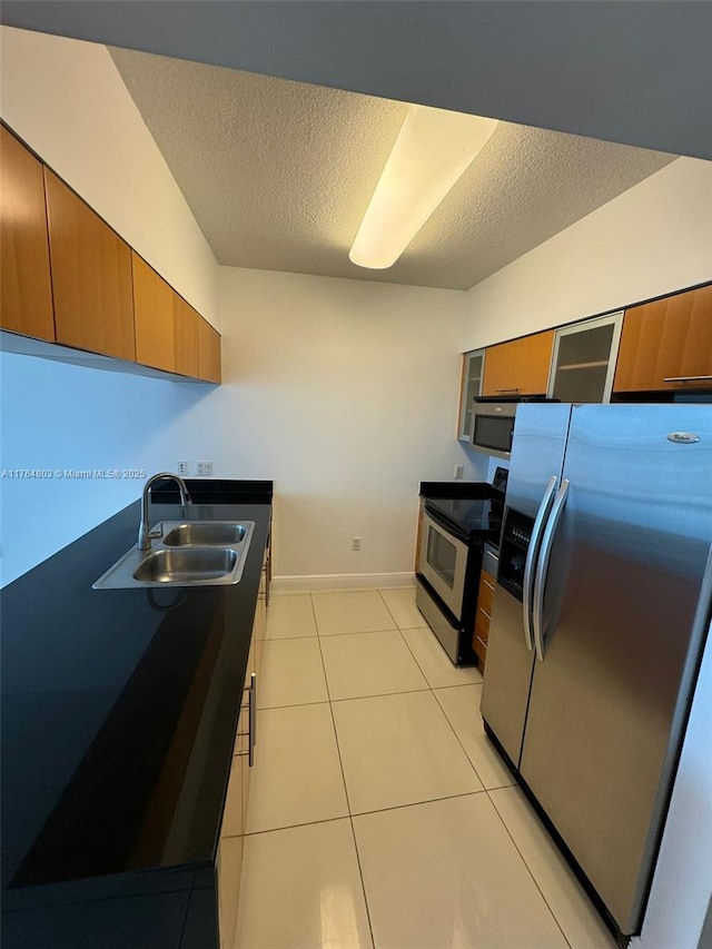 1750 N Bayshore Dr Unit 1606, Miami, FL 33132 - kitchen featuring stainless steel appliances, a sink, brown cabinetry, a textured ceiling, and baseboards
