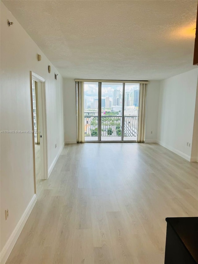 1750 N Bayshore Dr Unit 1606, Miami, FL 33132 - empty room featuring a textured ceiling, light wood finished floors, a wall of windows, and baseboards