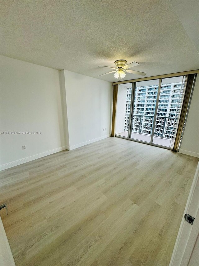 1750 N Bayshore Dr Unit 1606, Miami, FL 33132 - empty room featuring a ceiling fan, light wood-style flooring, baseboards, a textured ceiling, and a wall of windows