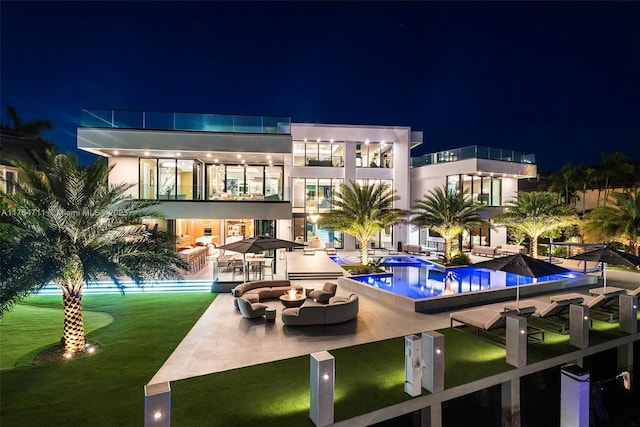 pool at night featuring a patio, a community pool, and a lawn