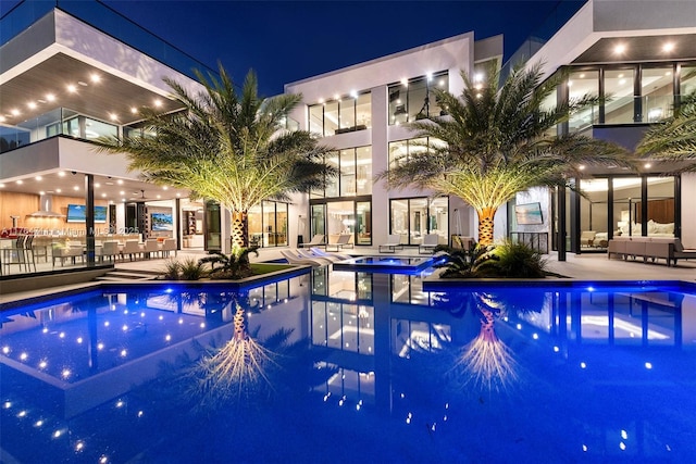 pool at twilight featuring a community hot tub, a community pool, and a patio area