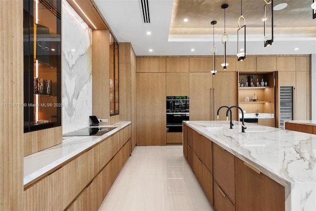 kitchen with black electric stovetop, modern cabinets, visible vents, and light stone countertops