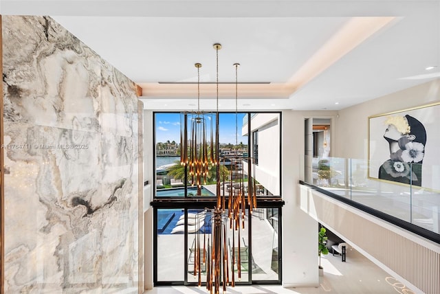 dining room featuring a chandelier, recessed lighting, a raised ceiling, and a water view