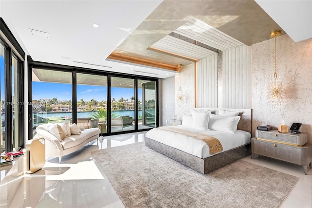 bedroom featuring access to exterior, a wall of windows, and a water view