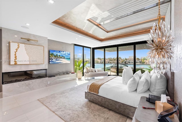 tiled bedroom featuring a wall of windows, a tray ceiling, access to outside, and a skylight