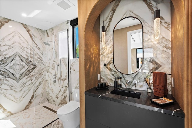 full bathroom with a marble finish shower, tile walls, toilet, vanity, and stone wall