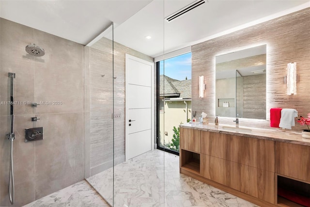 full bathroom with visible vents, marble finish floor, a walk in shower, tile walls, and vanity