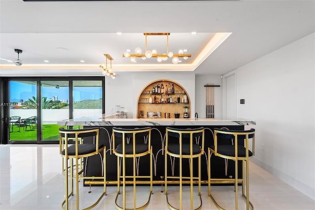 bar featuring pendant lighting, indoor wet bar, a raised ceiling, and baseboards