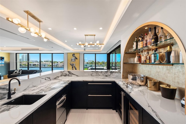 kitchen with a raised ceiling, dark cabinetry, and a sink