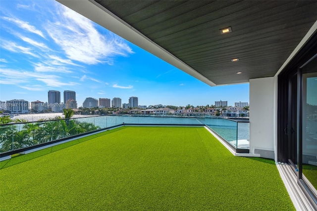 view of yard featuring a city view, a balcony, and a water view