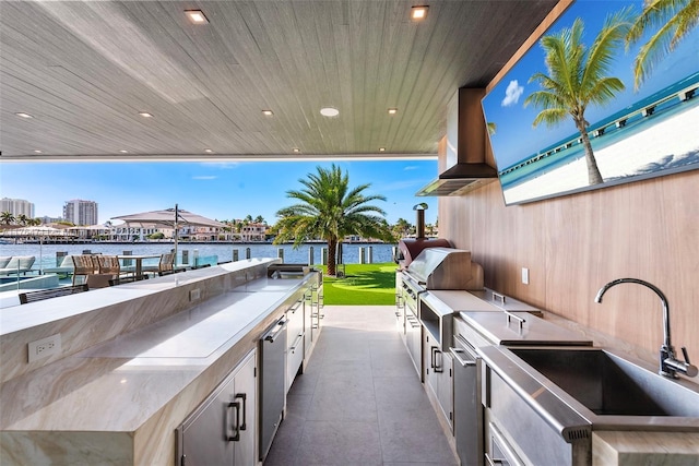 view of patio with area for grilling, a water view, and a sink