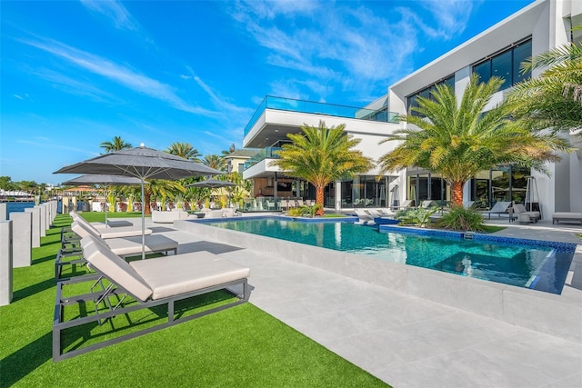 outdoor pool featuring fence, a patio area, and a lawn