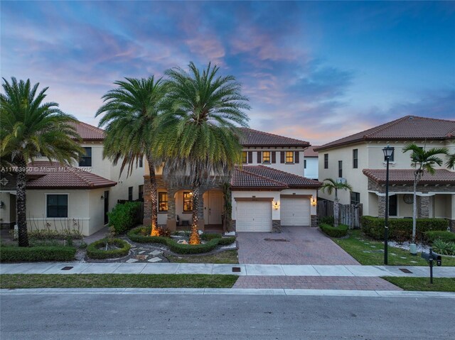 9835 NW 86th Ter, Doral, FL 33178 - view of front of house with stucco siding, a garage, stone siding, a tile roof, and decorative driveway