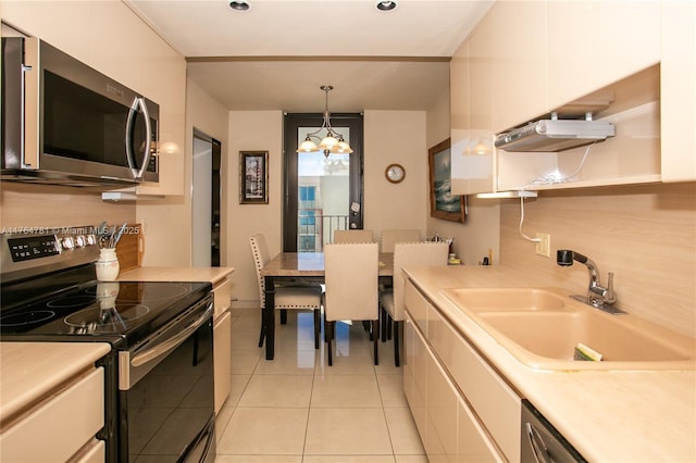 kitchen with an inviting chandelier, a sink, stainless steel appliances, light countertops, and white cabinetry