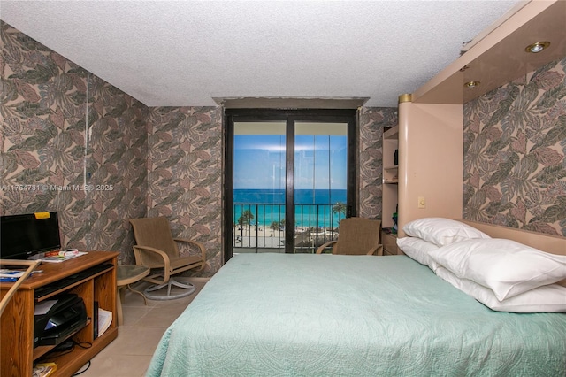 tiled bedroom featuring a textured ceiling, access to exterior, and wallpapered walls