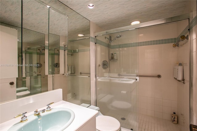 bathroom with toilet, a stall shower, and vanity