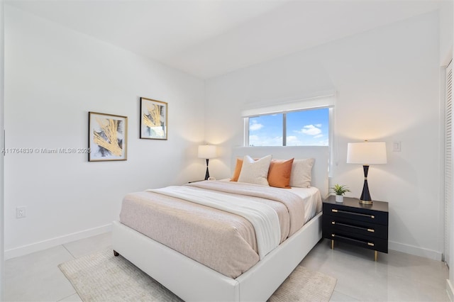 bedroom with light tile patterned flooring and baseboards