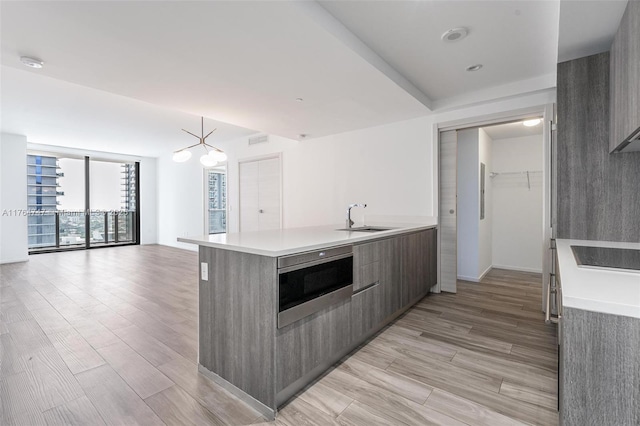 801 S Miami Ave Unit 3110, Miami, FL 33130 - kitchen featuring stainless steel microwave, modern cabinets, black electric stovetop, light countertops, and a peninsula