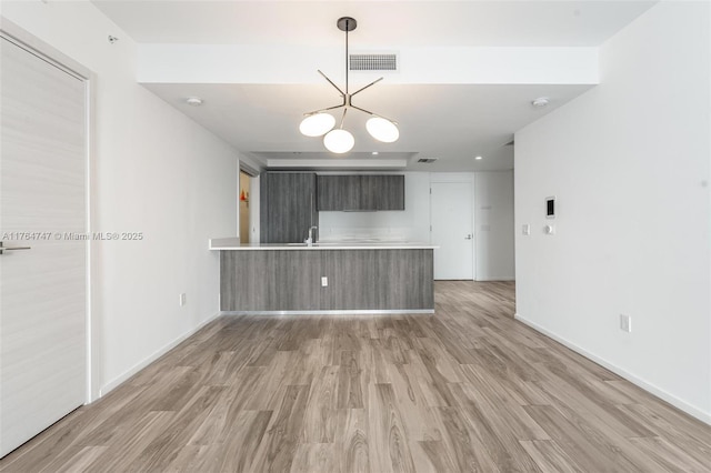 801 S Miami Ave Unit 3110, Miami, FL 33130 - kitchen featuring a peninsula, light countertops, light wood-type flooring, and a chandelier