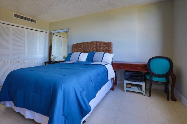 tiled bedroom with baseboards, visible vents, a closet, and a textured ceiling