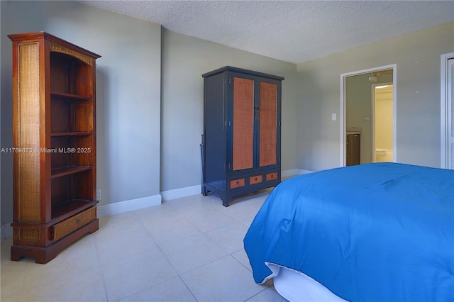 bedroom featuring light tile patterned floors, a textured ceiling, and baseboards