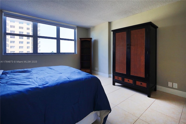 bedroom featuring light tile patterned floors, baseboards, and a textured ceiling