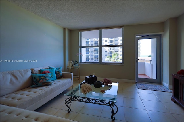 living area with baseboards, a textured ceiling, and light tile patterned flooring