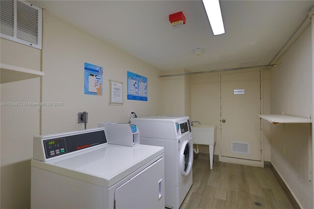 shared laundry area featuring visible vents, light wood finished floors, and washing machine and clothes dryer