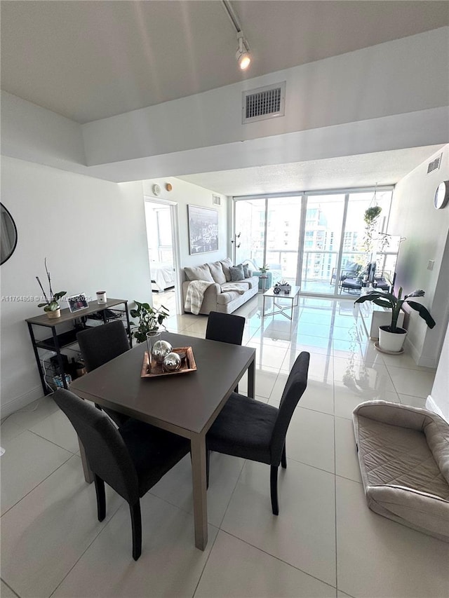 dining area featuring light tile patterned floors, visible vents, rail lighting, and baseboards