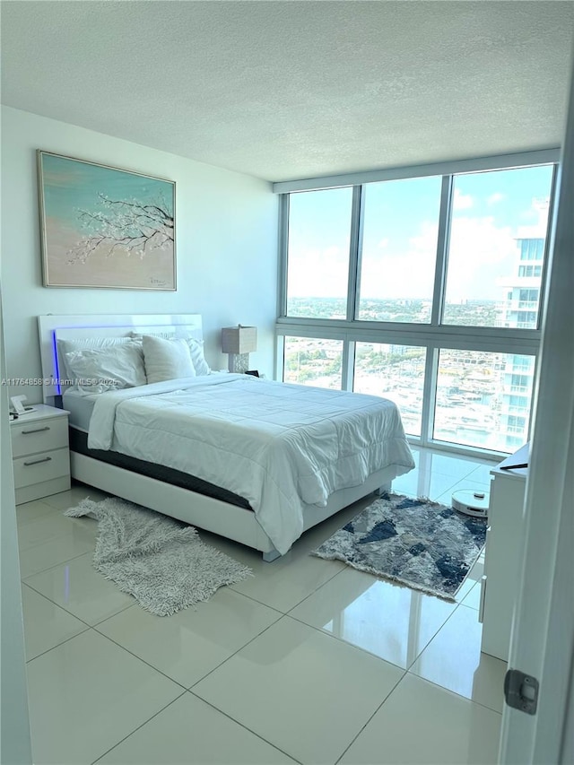tiled bedroom with a textured ceiling and a wall of windows
