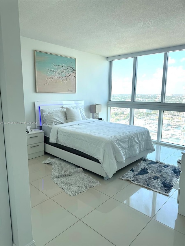 tiled bedroom with a textured ceiling and a wall of windows