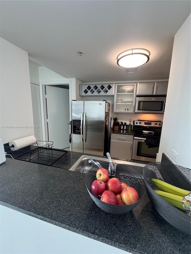 kitchen featuring dark countertops, glass insert cabinets, and stainless steel appliances