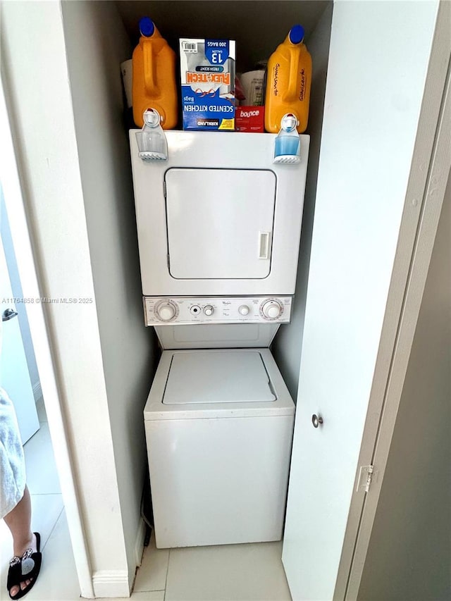 washroom with stacked washer and clothes dryer, laundry area, and tile patterned flooring