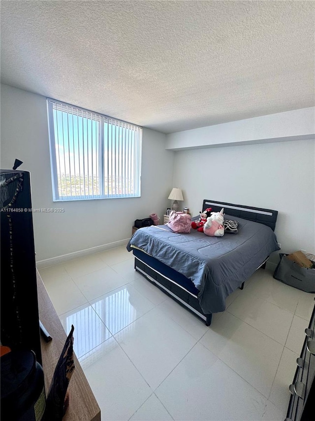 bedroom with tile patterned floors, baseboards, and a textured ceiling