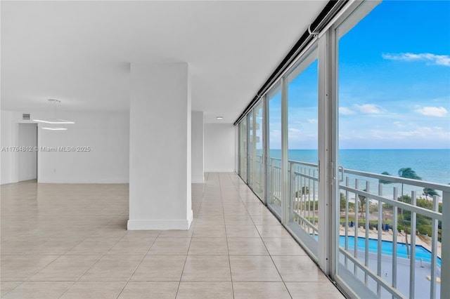 interior space with light tile patterned floors, baseboards, a water view, and expansive windows