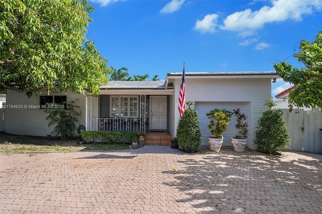 view of front facade featuring covered porch, stucco siding, and fence