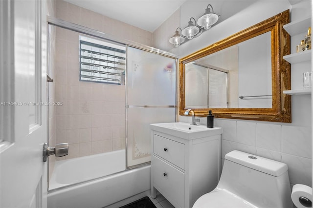 bathroom featuring toilet, enclosed tub / shower combo, vanity, and tile walls