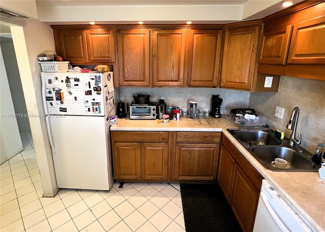 kitchen with light countertops, white appliances, a sink, and light tile patterned floors