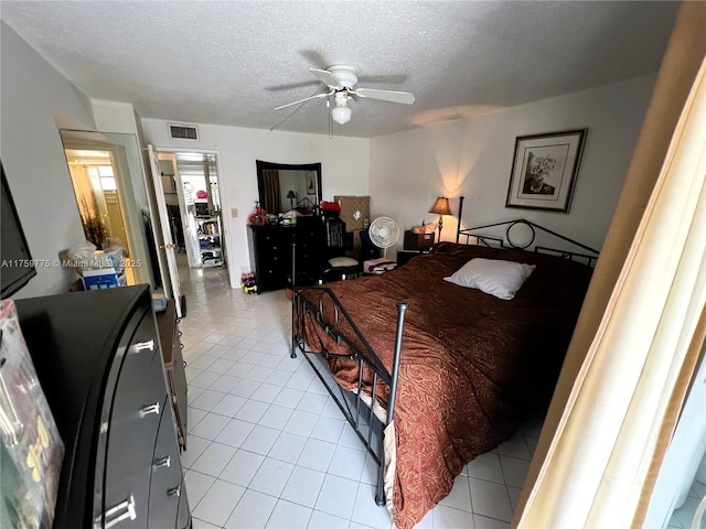 bedroom featuring visible vents, a textured ceiling, ceiling fan, and light tile patterned flooring