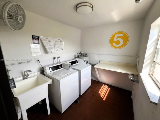 community laundry room with dark tile patterned floors, washing machine and clothes dryer, and a sink